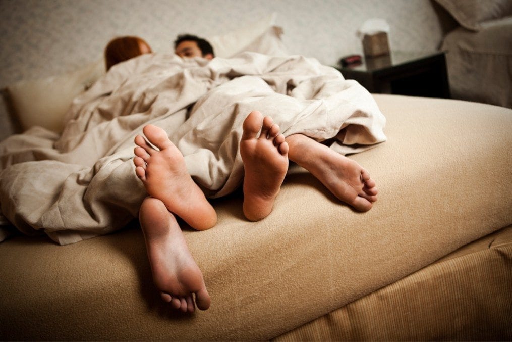 Couple in bed beneath the sheets