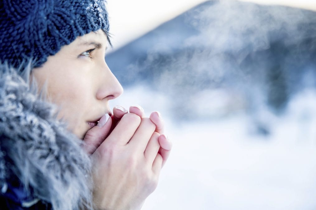 Woan blowing into hands in cold weather
