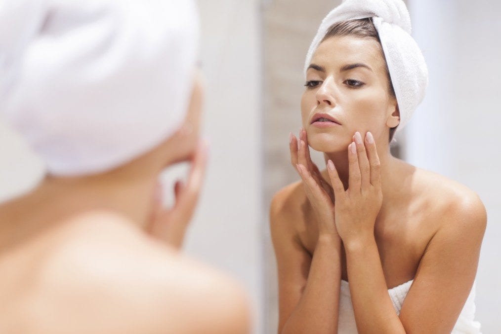 woman checking her face in the mirrir