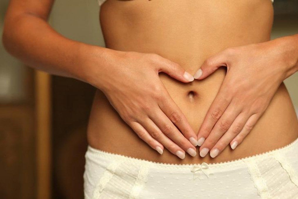 woman with palm on bare stomach
