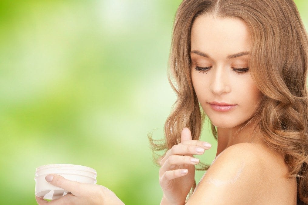 Woman applying organic cream on shoulder